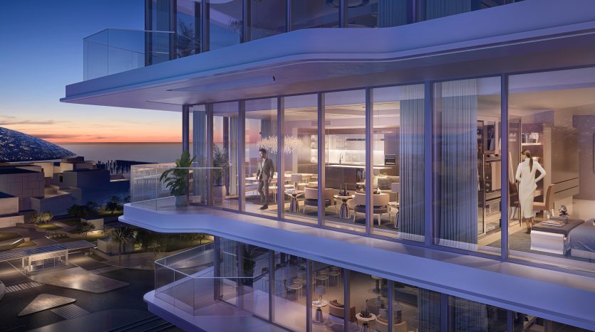 Une luxueuse façade d&#039;appartement moderne au crépuscule avec de vastes murs de verre, révélant des espaces intérieurs élégants. Une femme se tient à l’intérieur, près du balcon, surplombant les toits de Dubaï.