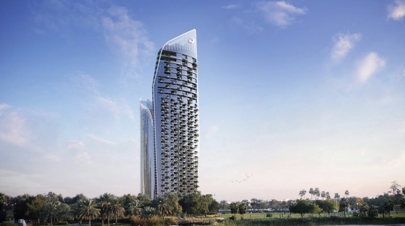 Un gratte-ciel moderne au sommet incurvé, doté d'une façade unique ornée de plantes, se dresse sur un ciel clair à Dubaï, entouré d'un parc verdoyant et luxuriant avec des palmiers.