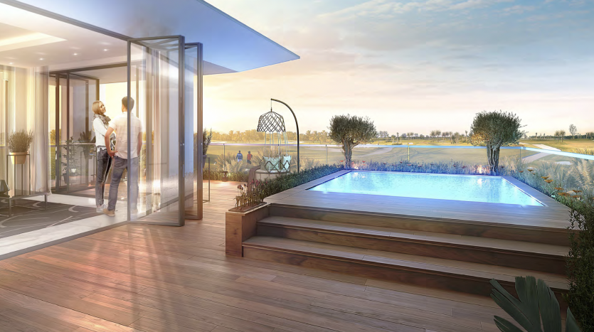 Un couple se tient devant des portes vitrées ouvertes menant à un balcon luxueux avec une petite piscine à débordement, surplombant un vaste paysage verdoyant au coucher du soleil dans leur villa à Dubaï.