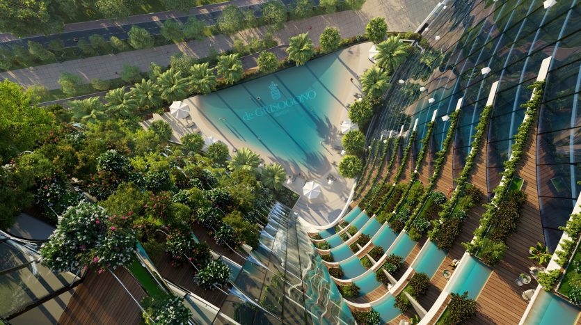 Vue aérienne d&#039;une villa moderne et curviligne à Dubaï recouverte de verdure, dotée de balcons et d&#039;un jardin sur le toit, entourant une piscine centrale bleue réfléchissante.