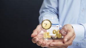 Homme en chemise bleue tenant une horloge et un graphique à barres avec des étincelles au-dessus des pièces de monnaie, représentant un concept abstrait de gestion du temps et de croissance des entreprises dans le secteur de l'investissement de Dubaï.