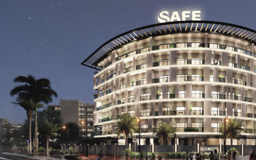 Un bâtiment d&#039;hôtel moderne illuminé la nuit avec le mot « coffre-fort » sur le toit, entouré de palmiers et d&#039;un paysage urbain à Dubaï.