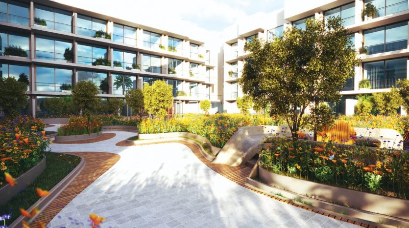 Allée de jardin luxuriante dans un complexe d'appartements moderne à Dubaï, avec des fleurs sauvages vibrantes, des bancs incurvés et des bâtiments contemporains sous un ciel clair.