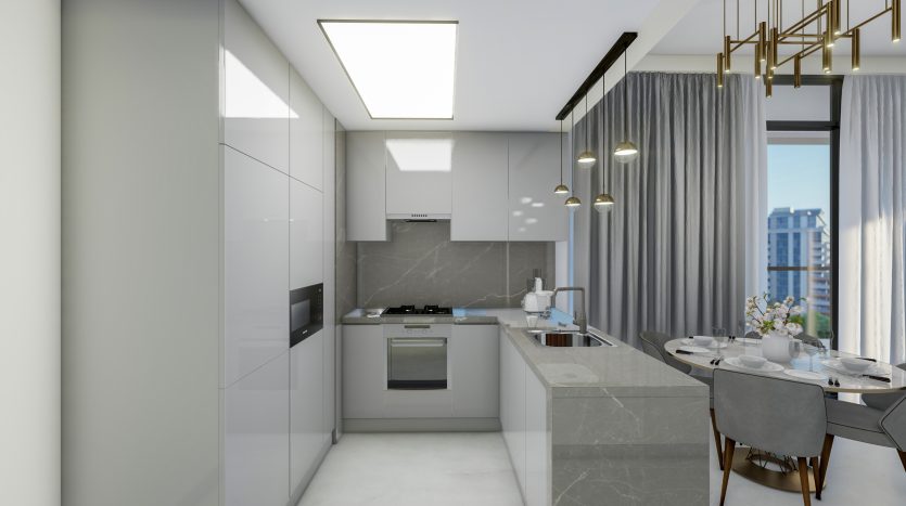 Intérieur de cuisine moderne avec armoires blanches élégantes, comptoirs en marbre et appareils électroménagers intégrés dans un appartement à Dubaï. Un coin repas avec une table ronde et des chaises est visible. Les grandes fenêtres offrent suffisamment de lumière naturelle.