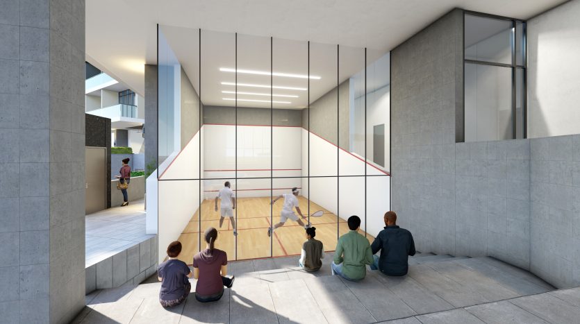 Des gens assis sur un rebord en béton regardent deux joueurs à l&#039;intérieur d&#039;un court de squash couvert avec des murs en verre dans un bâtiment urbain moderne à Dubaï.