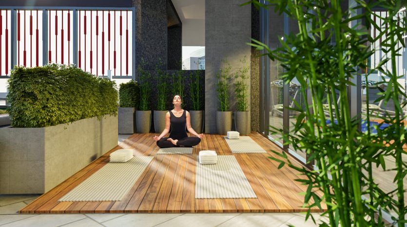 Une femme pratiquant le yoga dans un espace intérieur serein d&#039;une villa à Dubaï avec parquet, plantes en pot, paravents décoratifs et éléments architecturaux modernes.
