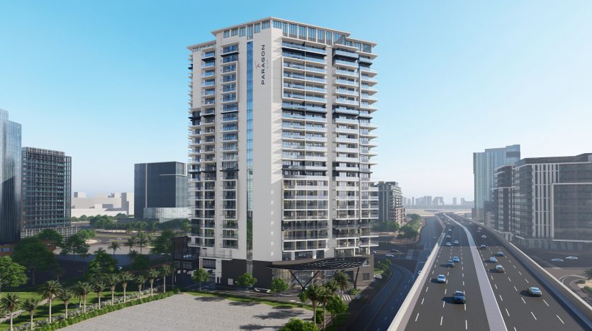 Un grand immeuble d&#039;appartements moderne doté de nombreux balcons se trouve à Dubaï, à côté d&#039;une autoroute où circulent des voitures, entouré d&#039;autres bâtiments urbains sous un ciel dégagé.