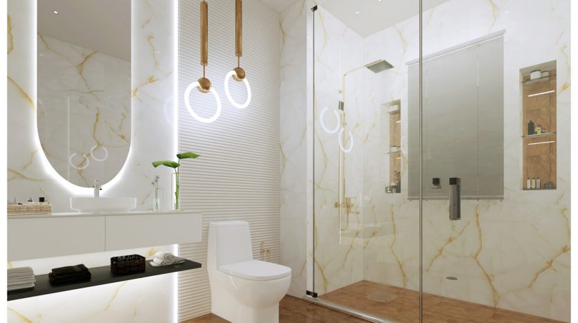 Salle de bains luxueuse avec murs et sols en marbre, cabine de douche en verre, miroir ovale avec suspensions, toilettes blanches et tapis texturé. Une touche de verdure est ajoutée par un petit