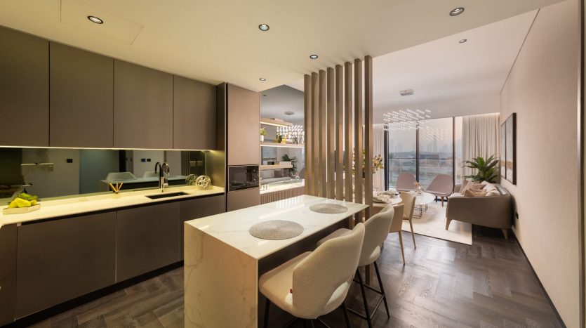 Une cuisine et un coin repas modernes et ouverts avec du parquet sombre, un îlot de cuisine en marbre, des armoires sombres et une table à manger installée dans une villa lumineuse et chaleureusement éclairée à Dubaï.