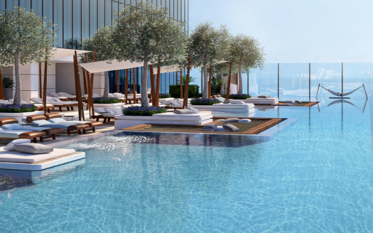 Une luxueuse piscine à débordement sur le toit avec de l'eau bleu clair, entourée d'arbres, de chaises longues et de cabanes, donnant sur une vue panoramique sur l'océan depuis un emplacement prestigieux de l'immobilier de Dubaï.