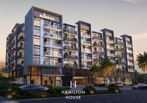 Moderno edificio residenziale a più piani all'imbrunire, con ampi balconi, grandi pannelli di vetro e l'insegna "Hamilton House". Palme rigogliose fiancheggiano la facciata. Perfetto per chi cerca