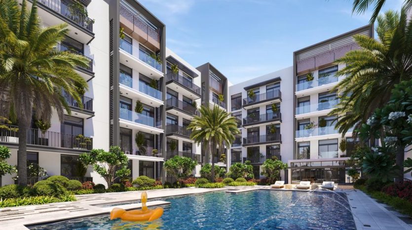 Un complexe résidentiel luxueux à Dubaï, avec des bâtiments à plusieurs étages entourant une grande piscine extérieure dotée d'un canard jaune flottant gonflable. Des palmiers luxuriants et des jardins paysagers rehaussent la scène tranquille.