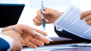 Deux professionnels de l'immobilier assis à un bureau, examinant et discutant d'un document immobilier lié à un appartement à Dubaï. Une personne tient le document tandis que l'autre tient un stylo, prête à prendre des notes ou