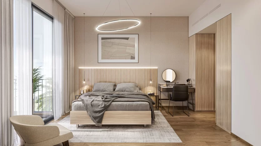 Une chambre moderne dans une villa de Dubaï avec des touches de bois et des tons neutres. Elle comprend un grand lit avec une literie grise, un miroir rond sur un bureau, une chaise et un éclairage d&#039;ambiance, dont un