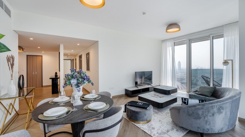 Salon d&#039;appartement moderne à Dubaï avec une décoration élégante, comprenant une table à manger ronde pour deux, un canapé incurvé moelleux et des fenêtres panoramiques avec vue sur la ville.