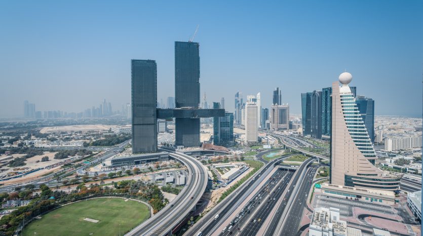 Vue aérienne d&#039;un paysage urbain moderne de Dubaï avec des gratte-ciel, des autoroutes très fréquentées et un ciel bleu clair.
