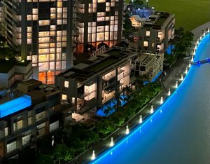 Vue aérienne d'un paysage urbain moderne la nuit, avec des bâtiments illuminés au bord d'une rivière bleue éclatante, avec une verdure luxuriante le long de ses rives à Dubaï.