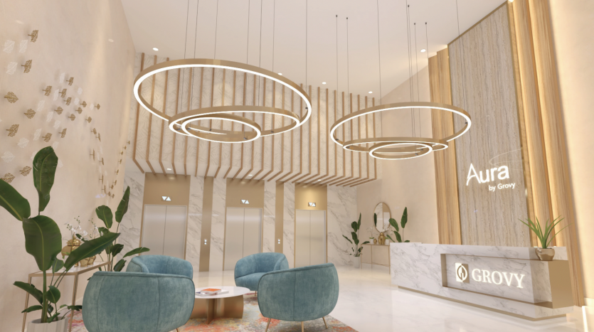 Un hall d'hôtel moderne doté d'élégants plafonniers circulaires, de murs en bois élégants et de chaises bleues moelleuses. La réception affiche le logo « Aura Immobilier Dubai by Grovy ».