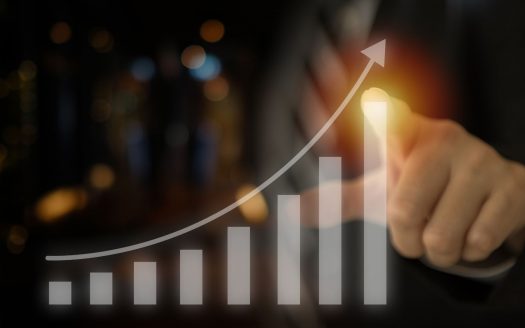 Un homme d'affaires montre une courbe de croissance virtuelle avec une flèche vers le haut, symbolisant une croissance ou un progrès positif de l'entreprise dans un cadre flou d'une agence immobilière de Dubaï.