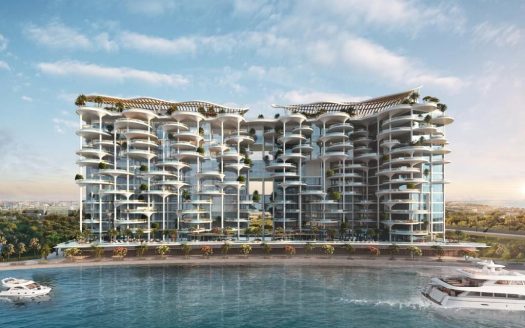 Un immeuble d'appartements moderne et luxueux en bord de mer à Dubaï avec plusieurs balcons, de vastes façades en verre et surmonté de toits verts. Plusieurs yachts sont amarrés à proximité dans un plan d’eau bleu clair.
