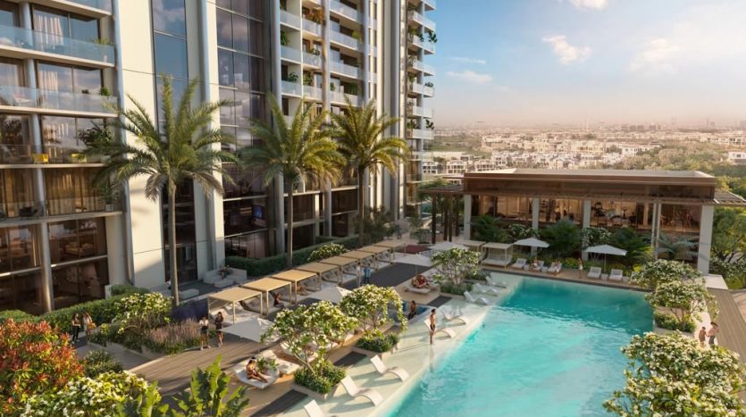 Vue d&#039;un complexe d&#039;appartements de luxe de grande hauteur à Dubaï, doté d&#039;une piscine extérieure entourée de palmiers, de coins salons et d&#039;un horizon de la ville en arrière-plan.