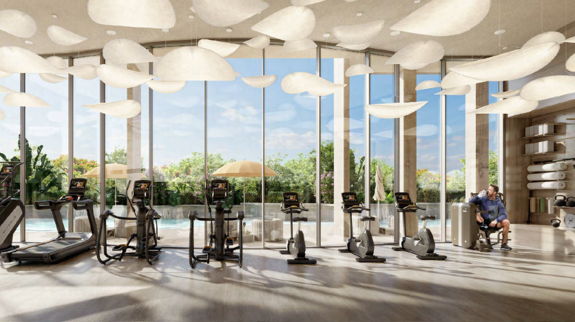 Une salle de sport moderne dans une villa de Dubaï avec de grandes fenêtres et des luminaires en forme de nuage fixés au plafond. Les appareils d&#039;exercice sont soigneusement disposés et un homme est assis, vérifiant son téléphone avec des plantes en arrière-plan.