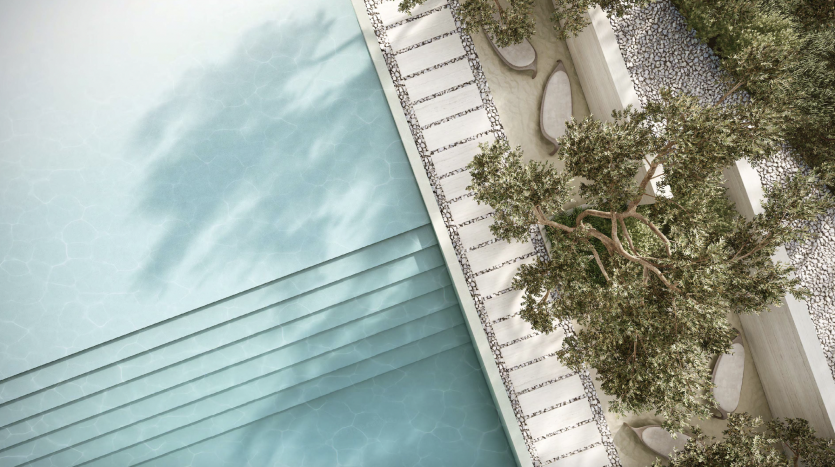 Vue aérienne d&#039;une luxueuse piscine aux eaux turquoise à côté d&#039;un patio carrelé blanc et d&#039;un jardin décoratif avec des arbres matures et des allées de galets dans une villa Dubaï.