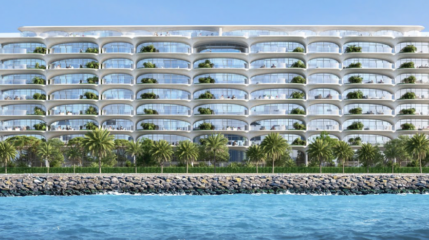 Un appartement moderne de plusieurs étages en bord de mer à Dubaï, avec des balcons incurvés, entourés de palmiers luxuriants et bordés par un brise-lames en pierre, vu depuis l&#039;eau.