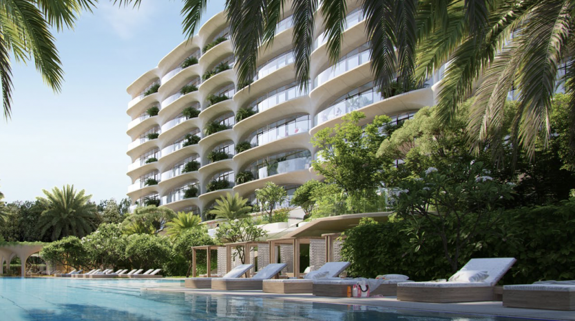 Immeuble d&#039;appartements de luxe moderne à Dubaï avec des balcons incurvés entourés d&#039;une verdure tropicale luxuriante et une piscine avec des chaises longues au premier plan.
