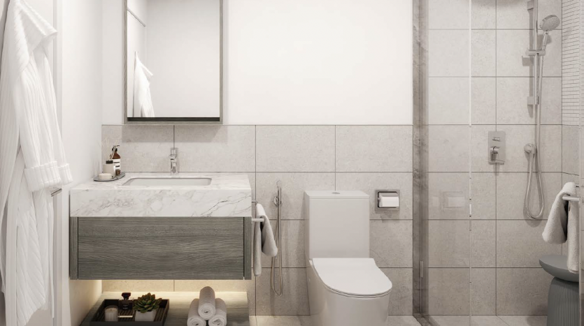 Une salle de bains moderne dans une villa de Dubaï avec une douche en verre, des toilettes blanches et une vanité avec un comptoir en marbre. Il y a des serviettes sur des supports et des articles de toilette soigneusement disposés sous l&#039;évier.
