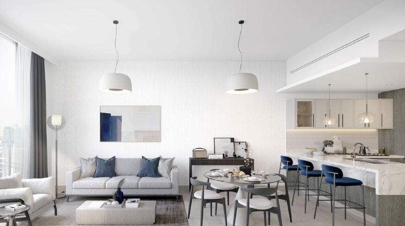 Intérieur d&#039;appartement moderne à Dubaï présentant un design décloisonné avec un salon et une cuisine. Le salon comprend un canapé, des chaises et une table basse, tandis que la cuisine est dotée de tabourets de bar et de luminaires suspendus.