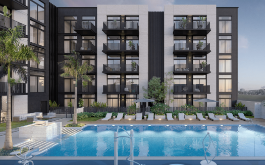 Immeuble d&#039;appartements moderne avec balcons donnant sur une piscine entourée de palmiers, de chaises longues et de fontaines, sur fond de front de mer à Dubaï.