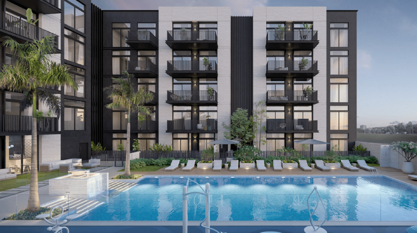Immeuble d&#039;appartements moderne avec balcons donnant sur une piscine entourée de palmiers, de chaises longues et de fontaines, sur fond de front de mer à Dubaï.
