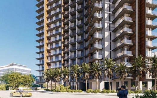 Un immeuble résidentiel moderne de grande hauteur avec de grands balcons, entouré de palmiers, sous un ciel bleu clair. Au premier plan, une voiture jaune passe et une personne prend une photo. Cette scène