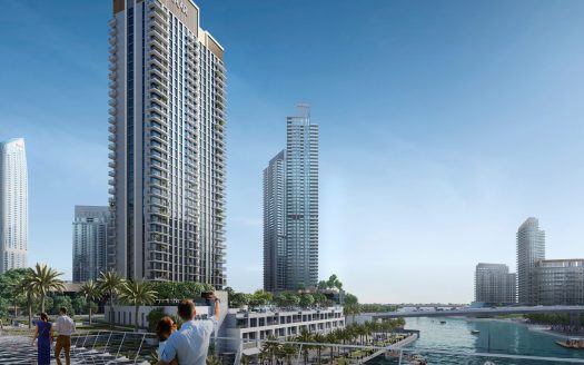 Trois personnes observant des gratte-ciel modernes depuis une promenade luxuriante au bord de l'eau à Dubaï, mettant l'accent sur le développement urbain et les vues panoramiques.