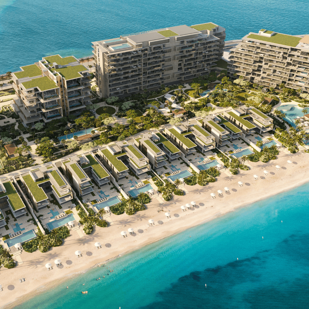 Vue aérienne d'une luxueuse station balnéaire avec des jardins luxuriants entre des bâtiments modernes, adjacente à une plage de sable immaculée aux eaux turquoise claires, idéale pour un investissement à Dubaï.