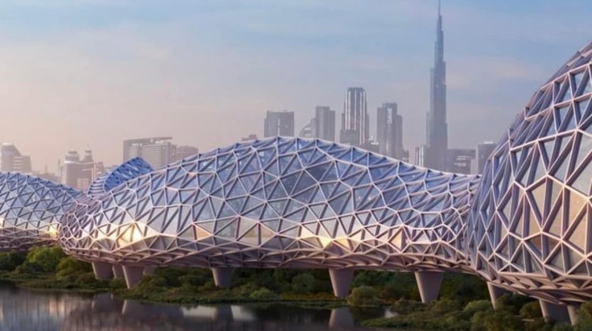 Architecture futuriste comprenant des dômes interconnectés avec un motif en treillis géométrique, sur fond de paysage urbain de Dubaï avec des gratte-ciel et une rivière au premier plan.