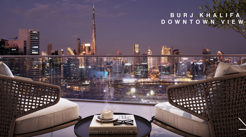 Vue depuis un appartement de grande hauteur à Dubaï avec deux chaises tressées et une table basse, surplombant le centre-ville de Dubaï et le Burj Khalifa illuminé la nuit.
