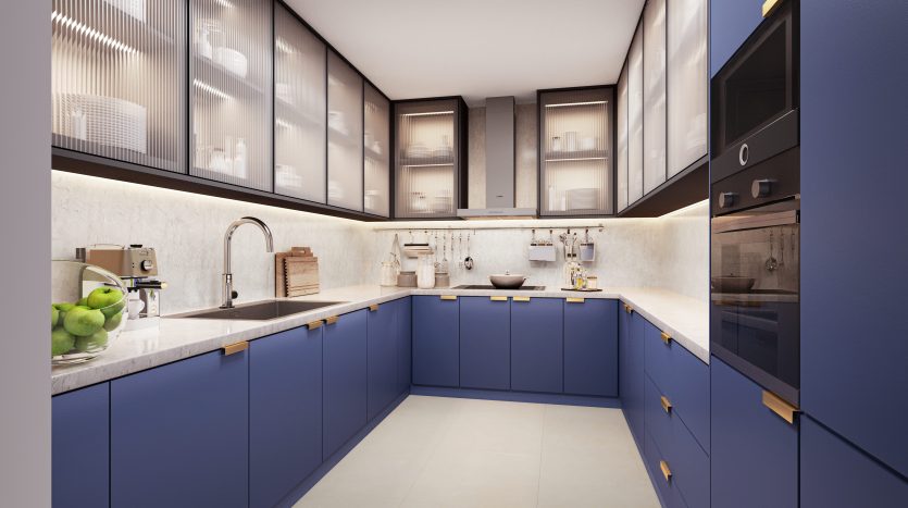 Une cuisine moderne dans un appartement de Dubaï avec des armoires bleues élégantes, des appareils électroménagers en acier inoxydable et des comptoirs blancs. La disposition en forme de U comprend des armoires supérieures à façade vitrée éclairées par un éclairage subtil.