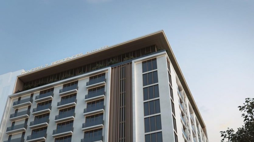 Vue en contre-plongée d&#039;un immeuble moderne de grande hauteur nommé &quot;Résidences Avancez&quot; sous un ciel bleu clair au coucher du soleil, commercialisé par une agence immobilière de Dubaï.