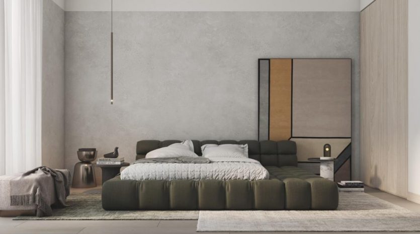 Une chambre minimaliste dans un appartement de Dubaï comprenant un grand lit vert avec un jeté texturé, une table d&#039;appoint avec des livres, une lampe et une grande peinture abstraite au-dessus du lit. La chambre est une salle de bain