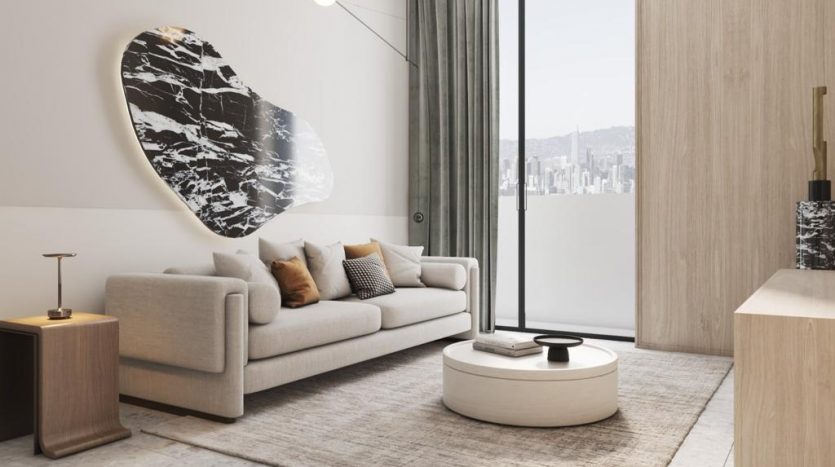 Salon moderne avec un canapé gris clair orné d&#039;oreillers, une grande œuvre d&#039;art ovale en noir et blanc au-dessus et une vue sur le paysage urbain à travers la baie vitrée présentant l&#039;immobilier Dubaï