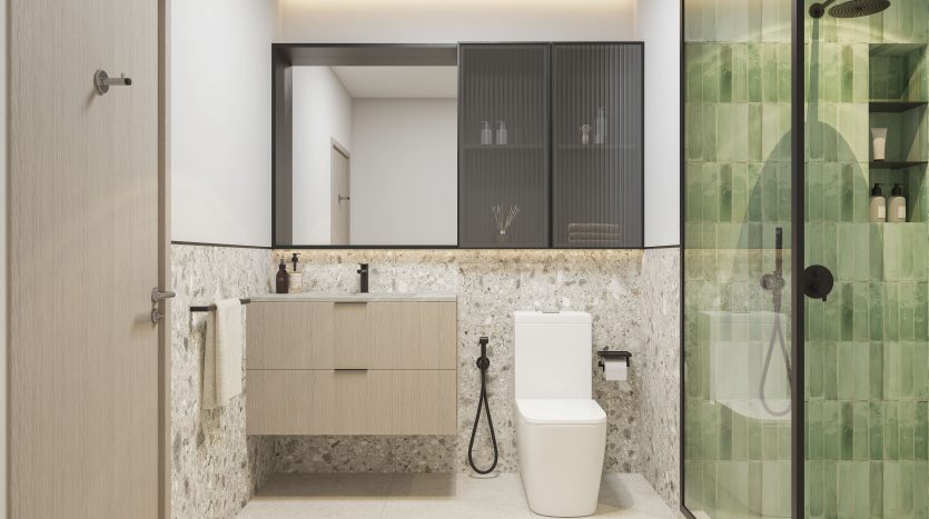 Une salle de bains moderne dans un appartement de Dubaï comprenant une cabine de douche en verre, un meuble-lavabo mural en bois avec lavabo, des toilettes blanches et des touches de carrelage vert sur les murs. Le sol est beige et