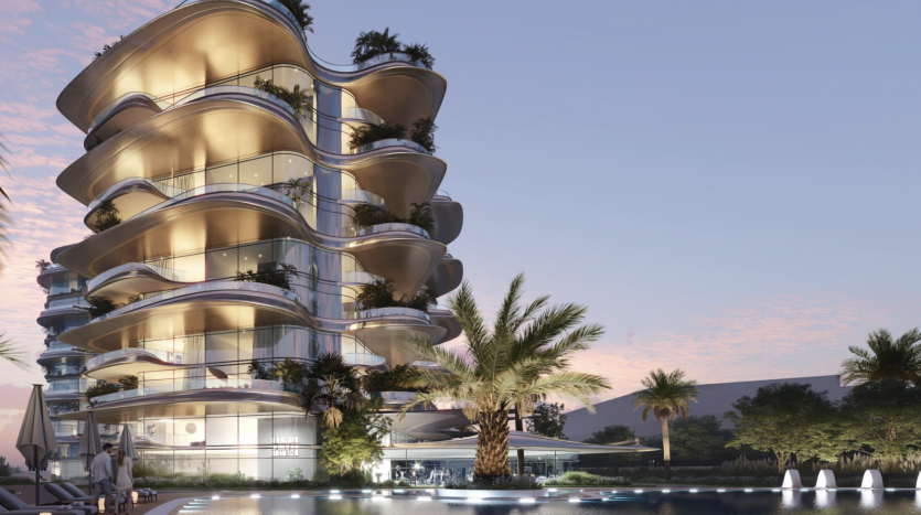 Bâtiment moderne de plusieurs étages avec des balcons incurvés éclairés par des lumières chaudes au crépuscule, entouré de palmiers et d&#039;un plan d&#039;eau réfléchissant au premier plan, une opportunité d&#039;investissement idéale à Dubaï.