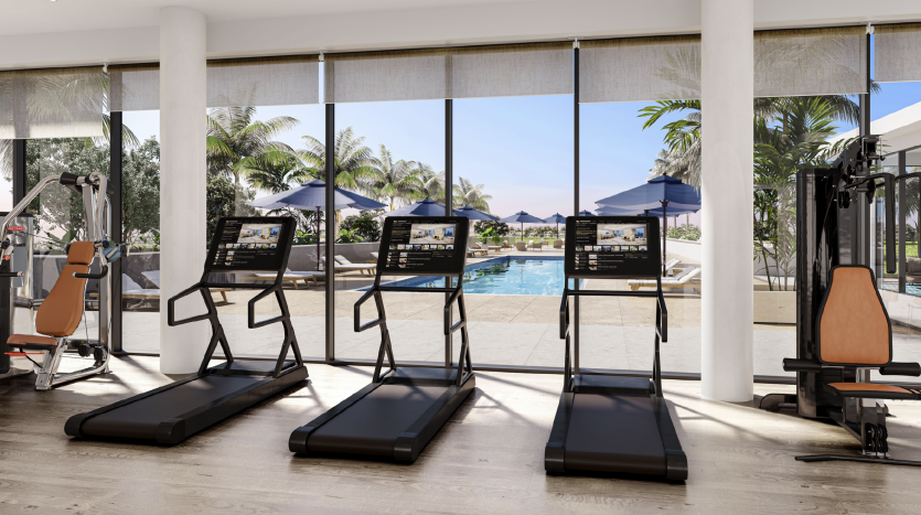 Une salle de sport moderne avec tapis roulants et équipements de musculation surplombe une piscine extérieure entourée de palmiers et de chaises longues relaxantes dans un luxueux appartement de Dubaï. Lumineux et spacieux, le quartier est inondé de nature