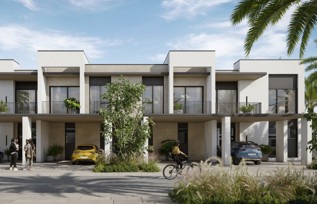 Complexe de villas modernes aux lignes épurées et aux couleurs neutres, avec résidents et véhicules à l'extérieur, entourés d'une verdure luxuriante et de palmiers sous un ciel dégagé.