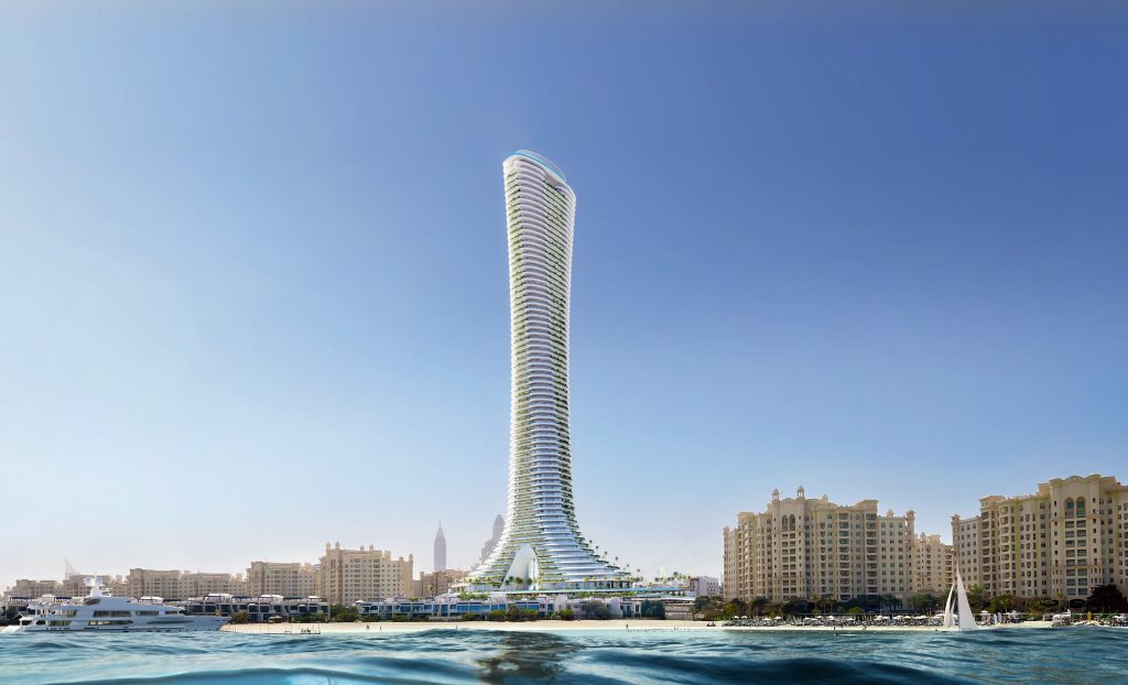 Un gratte-ciel futuriste et sinueux s&#039;élève bien en évidence au-dessus de l&#039;horizon côtier de Dubaï, flanqué d&#039;autres bâtiments et de bateaux naviguant sur des eaux bleu vif sous un ciel clair.