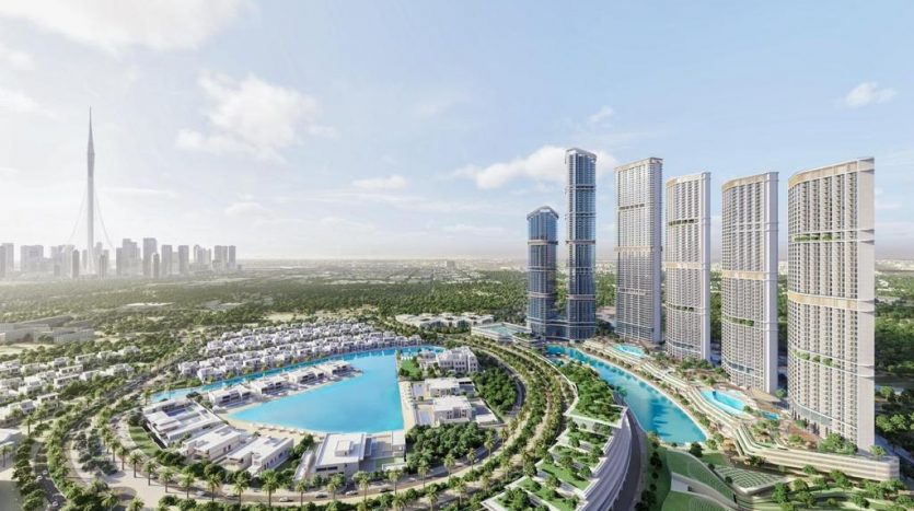 Vue aérienne d&#039;un développement urbain moderne à Dubaï avec des immeubles de grande hauteur, un grand lac artificiel et de vastes espaces verts, sous un ciel clair.