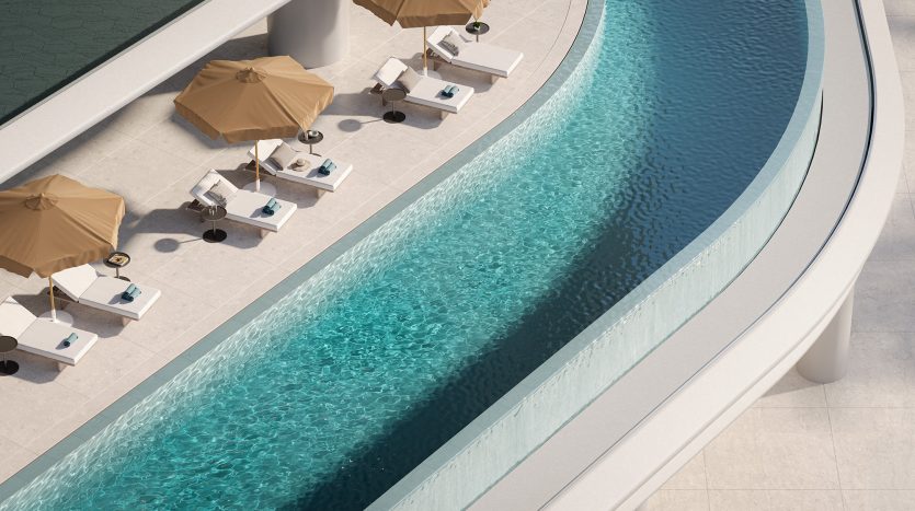 Vue aérienne d&#039;une piscine extérieure incurvée aux eaux bleues cristallines, entourée de parasols beiges et de chaises longues blanches dans une villa de luxe à Dubaï par une journée ensoleillée.