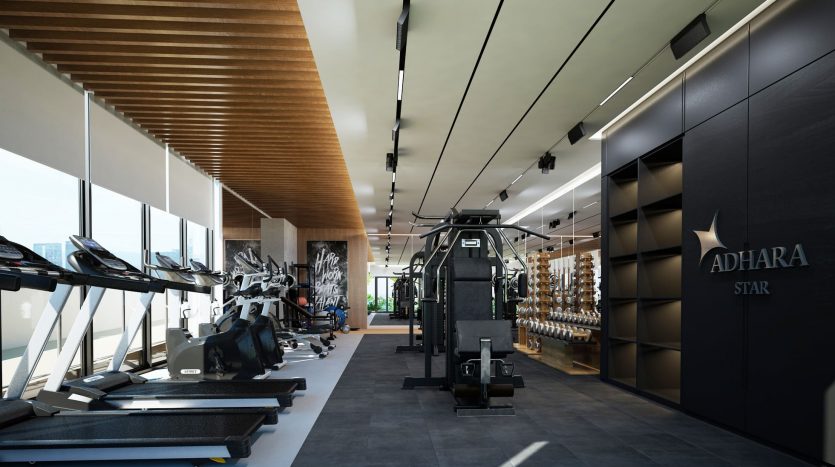Intérieur de salle de sport moderne comprenant une rangée de tapis roulants, des équipements de musculation, une grande machine à câble, divers haltères, le tout sous un plafond en bois avec un éclairage élégant à Dubaï.